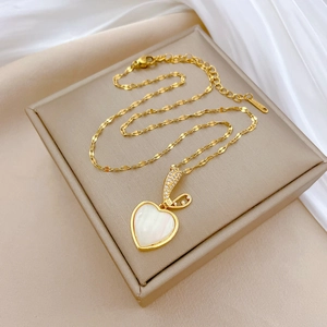 Close-up of golden heart pendant with mother-of-pearl shell inlay and sparkly crystals