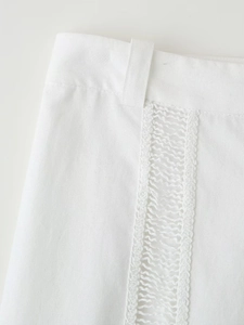 Détail du pantalon en lin blanc avec empiècements en dentelle complexe et boucles de ceinture