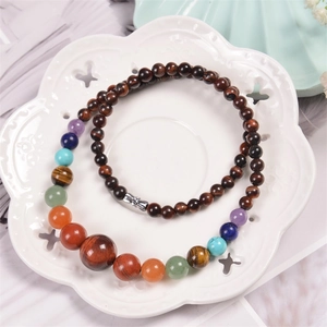 Macro shot of 6mm natural colorful gemstone beads and silver bow charm in ceramic bowl