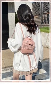Outdoor view of a mini pink floral backpack showing wear effect and compact size