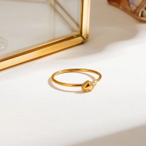 Close-up of heart-shaped gold stainless steel ring on a white display surface