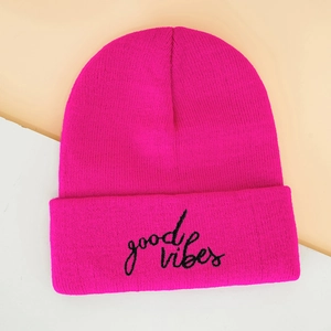 Close-up of rose red knit beanie showing black good vibes embroidery details