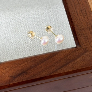 Detailed close-up of premium pink lustrous pearl earrings with high-gloss finish