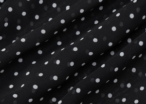 Vista macro dettagliata del tessuto in chiffon nero a pois bianchi con consistenza morbida