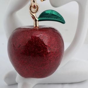 Macro view of a red glitter apple keychain with a gold leaf and metal ring attachment