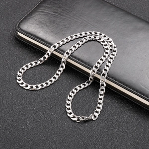 Polished silver cuban link chain necklace resting on black leather texture background