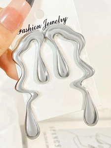 Detailed macro view of liquid metal style irregular silver teardrop earrings on a card