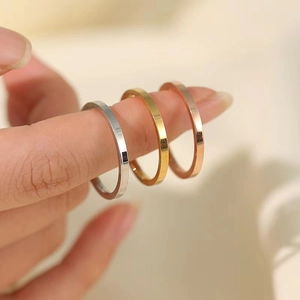 Minimalist 2mm titanium steel rings in silver, gold, and rose gold on a model's hand