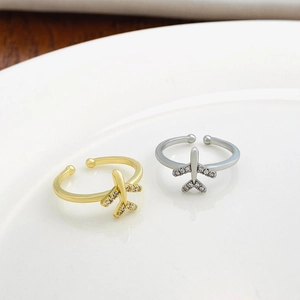 Close-up of gold and silver airplane rings with sparkling crystals on ceramic plate