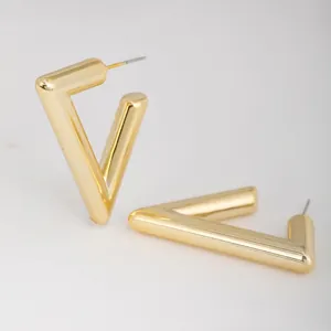 Close-up of polished gold V-shaped geometric earrings in minimalist style