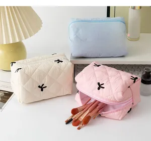 Beauty case trapuntati blu, crema e rosa con fiocchi neri e chiusura con cerniera lampo