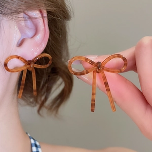Détail des boucles d'oreilles nœud en acétate ambré montrant la texture rayée rétro
