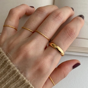 Golden stackable ring set with twisted texture and smooth bands on a hand