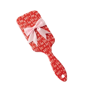 Christmas air cushion hairbrush with red ho-ho-ho pattern and pink ribbon bow on white background