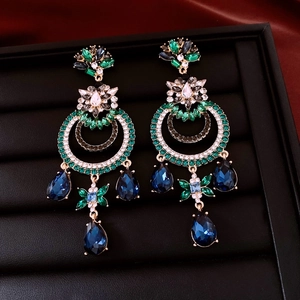 Détail de boucles d'oreilles style vintage avec cristaux émeraude et bleus brillants