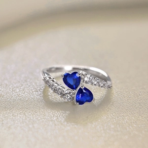 Macro shot of two blue heart-shaped zircons and side diamonds on S925 silver ring