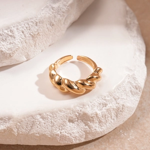 Dettaglio di un anello aperto a spirale dorato su una pietra naturale bianca testurizzata