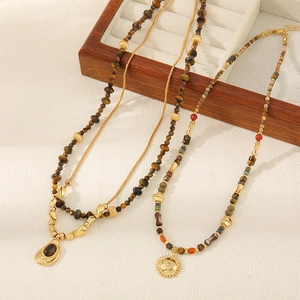 Detail view of retro beaded necklaces with sun pendant and drop gemstone in earthy tones