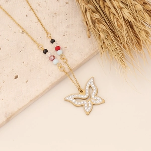 Golden butterfly necklace with colorful beads on a minimalist stone display