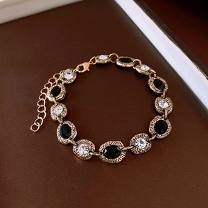 Detail of vintage gold bracelet featuring black and clear stones with lobster clasp closure