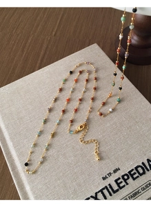 Detailed macro of a colorful bead necklace with gold chain on a textile book cover