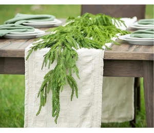 Close-up of cream cotton linen table runner with fringe edge on rustic wooden table