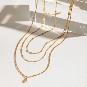 Detail of layered gold stainless steel necklace featuring a teardrop pendant and crystal accents