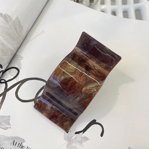 Macro detail of tortoiseshell acrylic hair clip texture on minimalist magazine background