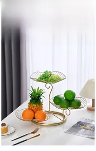 Close-up of three-tier leaf-shaped gold metal fruit basket for home storage and decor
