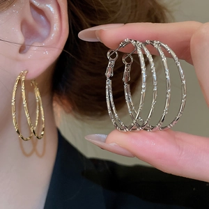 Detail of bamboo texture double hoop earrings shown in gold and silver metal finishes