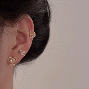 Detail of golden heart and star clip-on earrings with blue stones on ear