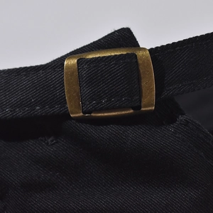 Detailed close-up of adjustable cotton strap and bronze metal buckle on black baseball cap