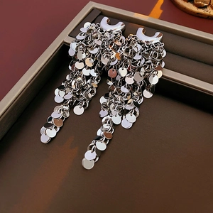 Détail de boucles d'oreilles argentées à franges et paillettes sur un plateau à bijoux