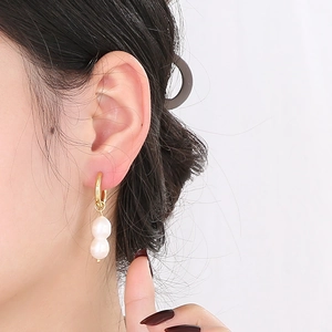 Boucles d'oreilles vintage en perles et acier titane plaqué or 18k portées par mannequin