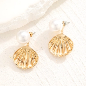 Detail of shell-shaped gold earrings featuring lustrous white pearls and textured lines