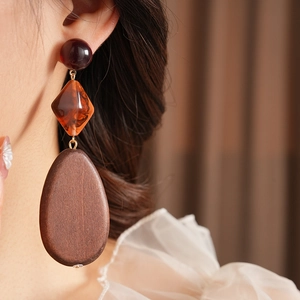 Detailed close-up of amber resin and wood teardrop earrings worn by a model