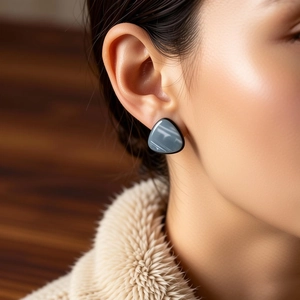 Close-up of minimalist triangle resin earring in blue grey finish worn by a model