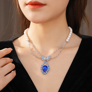 Close-up of vintage bow necklace with pearl chain and blue teardrop rhinestone pendant