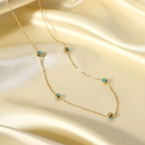 Detail of 18K gold-plated necklace with five turquoise blue evil eye beads on silk