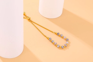 Detailed shot of gold beaded bracelet with lilac faceted gems and adjustable chain