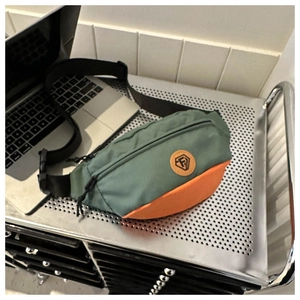 Detail of color-block sports waist bag in dark green and orange with adjustable strap