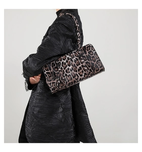 Leopard print baguette shoulder bag styled with a textured black coat on a female model