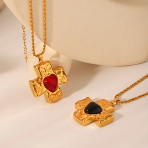 Detail of hammered gold cross pendants with red and black heart-shaped stone inlays