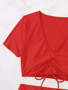 Detail of red V-neck drawstring bikini top with pleated short sleeves on marble background