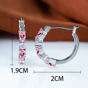 Macro detail of silver hoop earrings with pink and clear zircon stones measuring 2cm