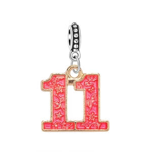 Detailed view of pink enamel number 11 charm pendant with golden floral engraved texture