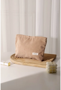 Khaki corduroy makeup bag on a wooden tray with a minimalist aesthetic detail