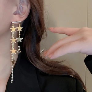 Gros plan de boucles d'oreilles étoiles dorées avec de longs glands en strass