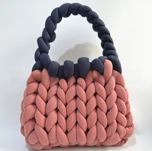 Detail of chunky knit candy color handbag with contrasting navy blue woven handle