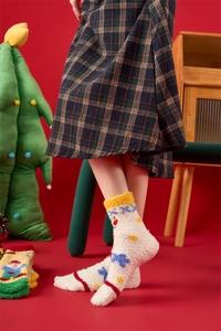 Detail of warm coral fleece Christmas socks with embroidered patterns on red background